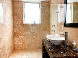 Une salle de bain avec une douche à parois de verre, un lavabo blanc et un comptoir en marbre.