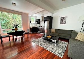 A modern living room with a sofa, a coffee table, and a dining area with a table and chairs.