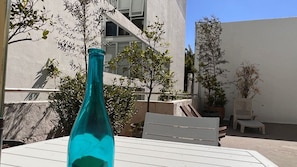 A patio area with a white table, a blue bottle, and potted plants.