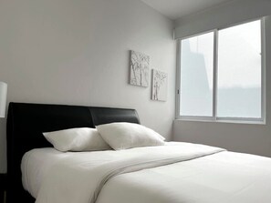 A bedroom with a bed, a window, and two wall-mounted artworks.
