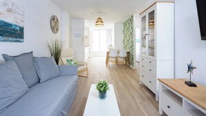 Un salon moderne avec un canapé, une table basse agrémentée d’une plante, un meuble et un téléviseur fixé au mur.