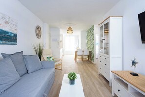 A modern living room with a sofa, a coffee table with a plant, a cabinet, and a TV on the wall.