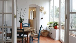 A dining area with a round table, chairs, and potted plants. - Location, unique charm, beach, pool, forest, comfort, 360º views (Malveira da Serra)