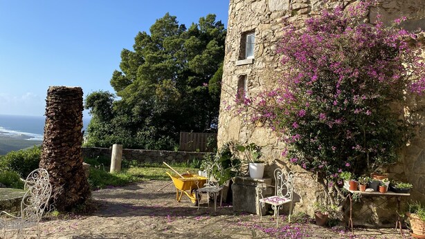 A stone building with a tiled roof, a small window, and a balcony with potted plants. - Location, unique charm, beach, pool, forest, comfort, 360º views (Malveira da Serra)