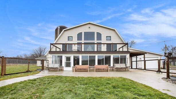 A two-story house with a large front porch, a covered patio, and a fenced backyard. - Renovated Dairy Barn – 4 Bedrooms, 5 Beds, 2.5 Baths, Huge, Accessible & Stylish (Byron Center)