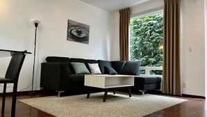 A modern living room with a black sofa, a white coffee table, and a floor lamp. - Condesa Residence Amsterdam 203 (Ciudad de México)