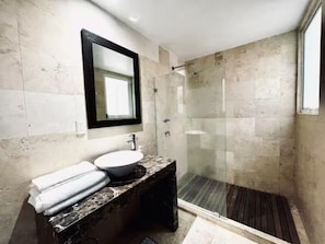 Un bagno moderno con cabina doccia in vetro, lavabo in marmo e specchio integrato.