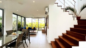 Un intérieur moderne comprenant un coin repas, un escalier et de grandes fenêtres.