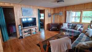 A wooden-paneled living room with a television, sofa, and a fireplace.