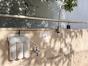 Sistema de filtración de agua con tres botellas etiquetadas 'bebbia' y un cartel de filtro de agua.