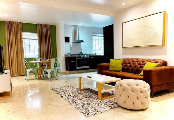 Una sala moderna con sof á, reposapiés, mesa de centro y un comedor con sillas y una mesa.