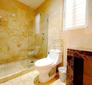 Un bagno con il water, uno spazio doccia in vetro e un pavimento piastrellato in marmo.
