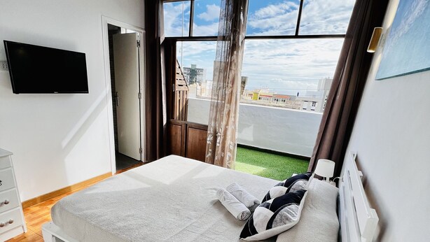 Een slaapkamer met een bed, een televisie, een raam met uitzicht en een houten vloer.