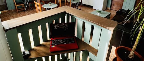 Cocina pequeña con armarios blancos, comedor con sillas de madera y un ordenador portátil sobre una banca.