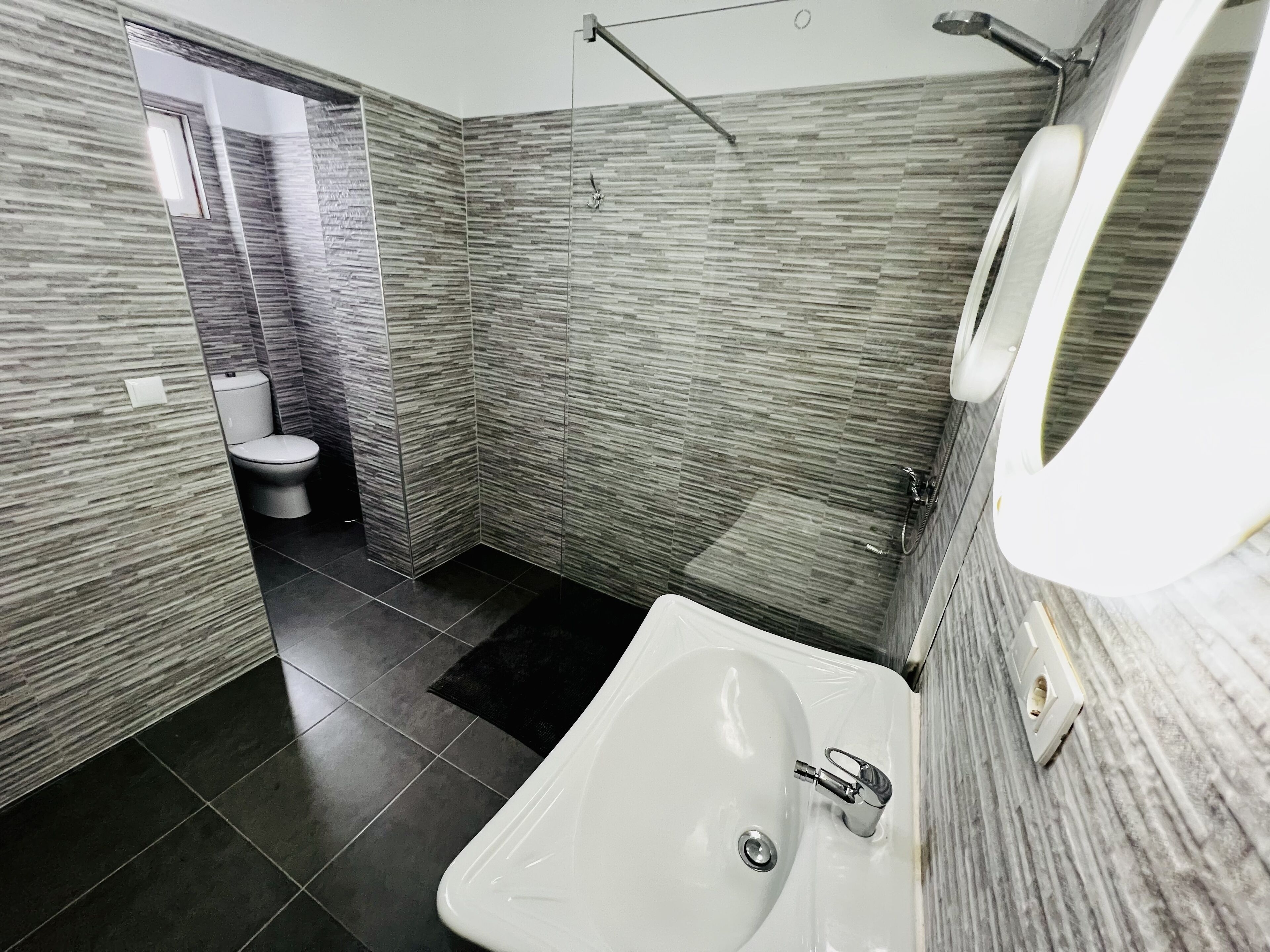 Un baño moderno con lavamanos blanco, inodoro y zona de ducha.