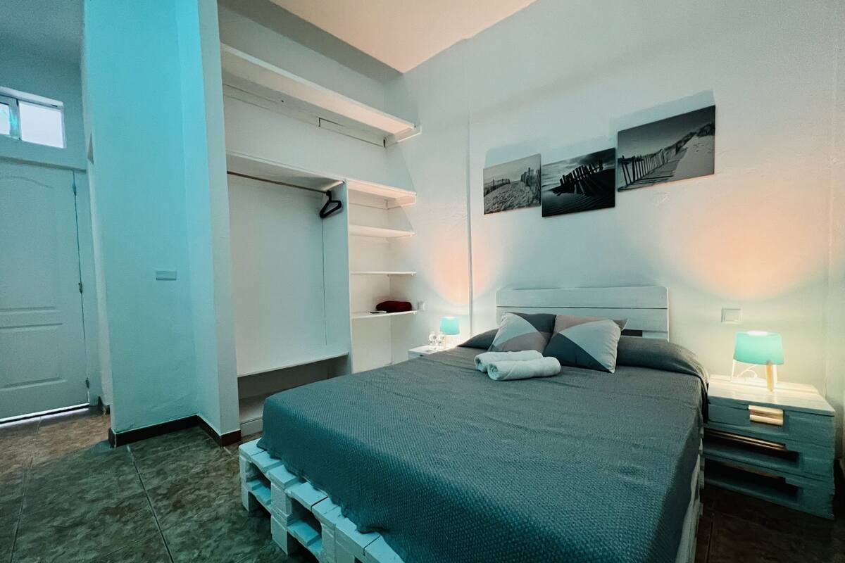 A bedroom with a bed, bedside tables, a wardrobe, and a wall-mounted shelf.
