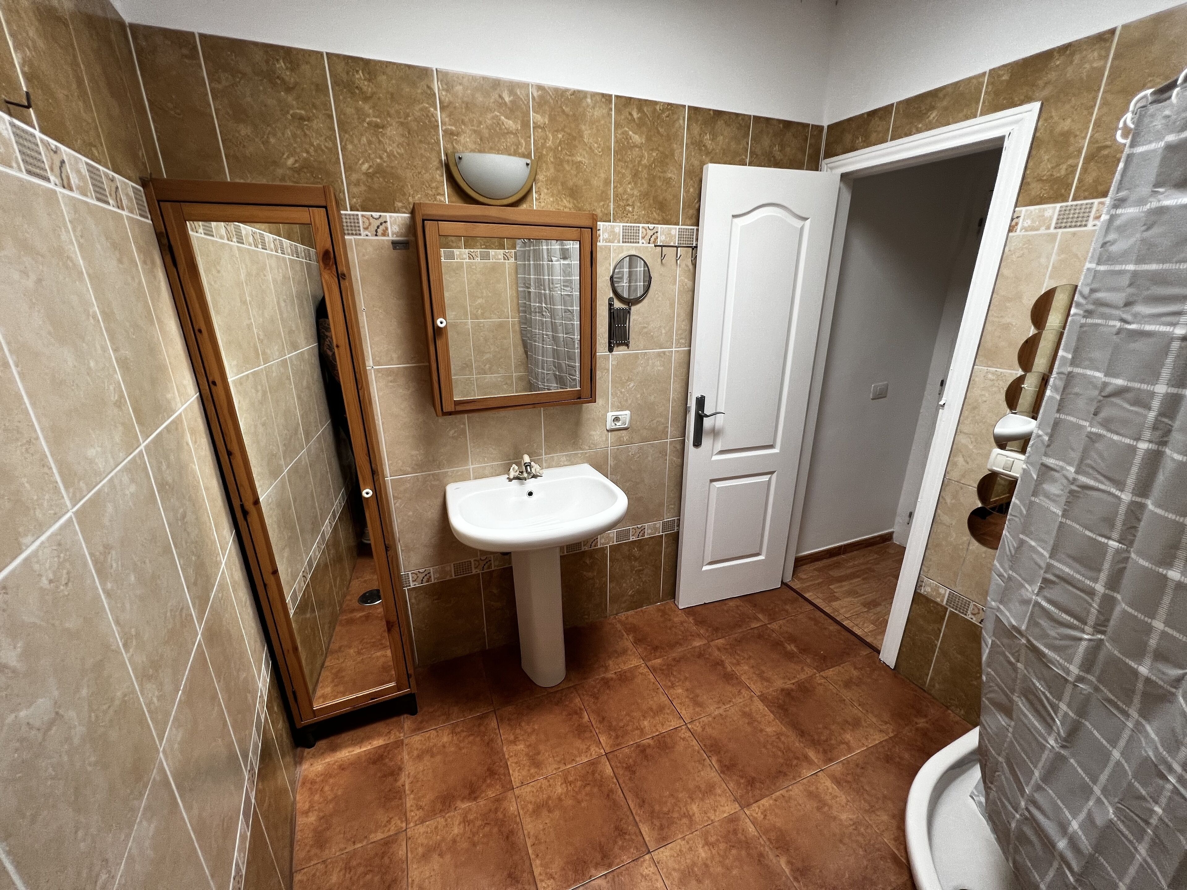 A bathroom with a sink, mirror, and door.