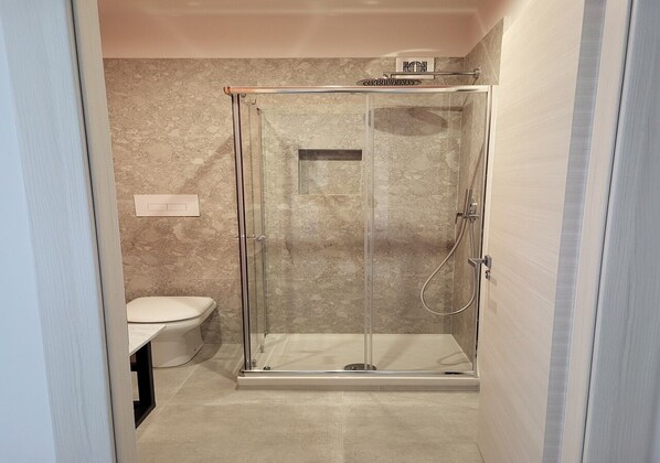 Un baño con ducha de vidrio, inodoro y perchero para toallas.