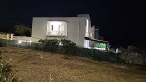 A modern building with a balcony, a fenced area, and a dry grassy field. - Casa Villaggio Pirandello (Agrigento)
