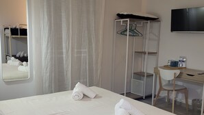 A hotel room with a bed, a desk, a chair, a wardrobe, a mirror, and an air conditioning unit. - Casa Villaggio Pirandello (Agrigento)
