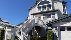 A two-story house with a white exterior, a garage with the number 1225, and a staircase leading to the upper floor. - Beach Access, Pools, Tennis and Pickleball - 1225 Gulf & Bayside (Siesta Key)