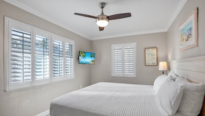A bedroom with a bed, a ceiling fan, a TV, and a wall-mounted lamp. - 15 SS Cottage - Close to Beach and Village (Siesta Key)