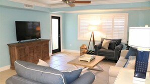 A living room with a sofa, a coffee table, a TV, and a lamp. - 303 Sea Shell- Beautifully Updated Gulfside Condo (Siesta Key)