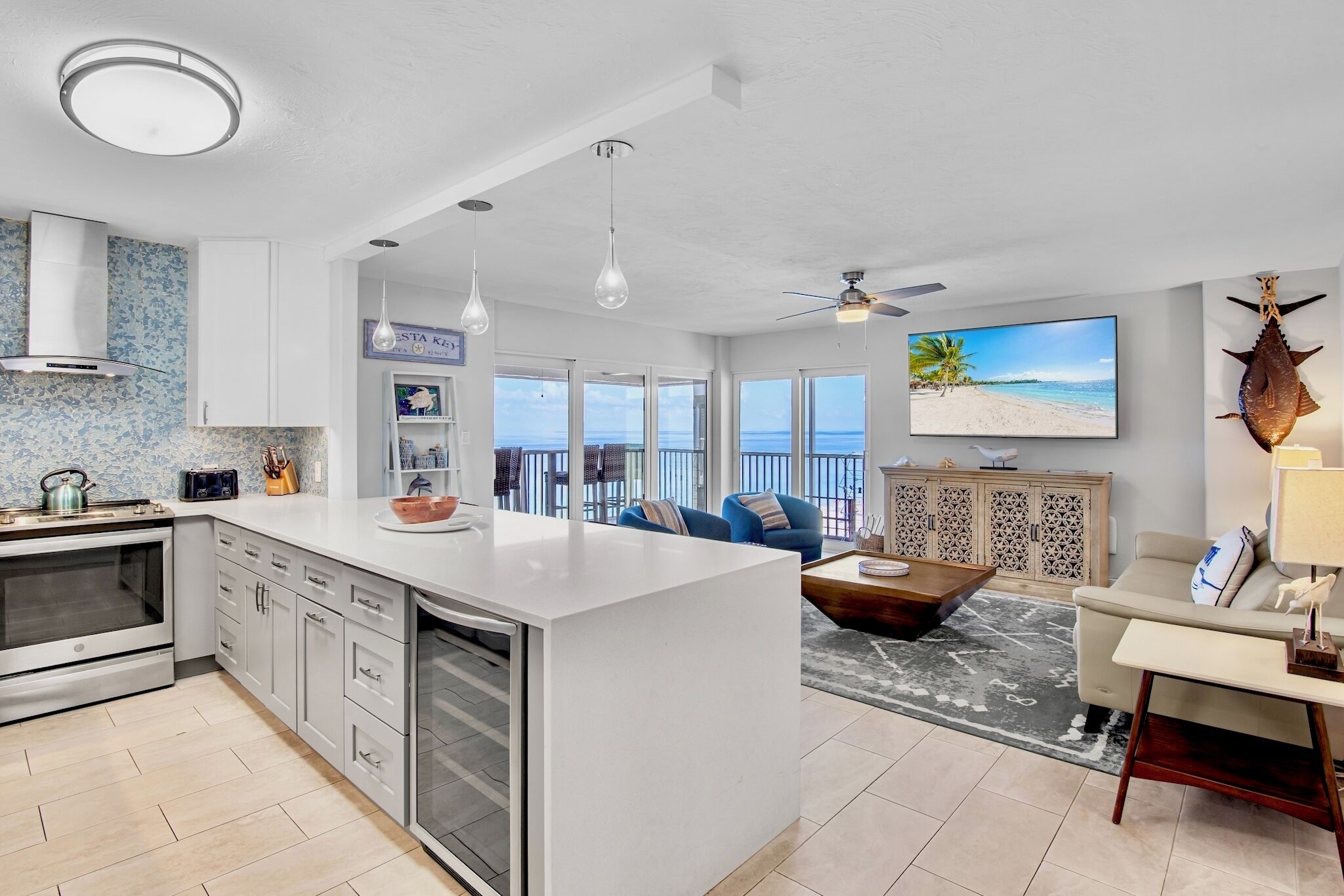 A modern kitchen with a large island, a dining area with a view, and a living room with a sofa and coffee table.