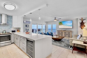 A modern kitchen with a large island, a dining area with a view, and a living room with a sofa and coffee table.