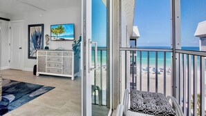 A room with a view of the beach, a white dresser, and a television.