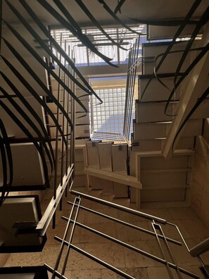 A staircase with metal railings and a view of a tiled floor through a window.