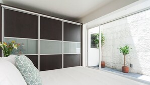 Un dormitorio con una cama grande, una puerta corredera y vistas al exterior.