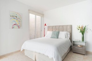 A bedroom with a bed, a bedside table, a lamp, and a wall art piece.