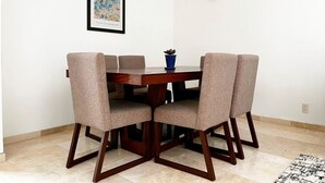 Un comedor con una mesa de madera y cuatro sillas tapizadas. En la pared, encima de la mesa, hay una obra de arte enmarcada.