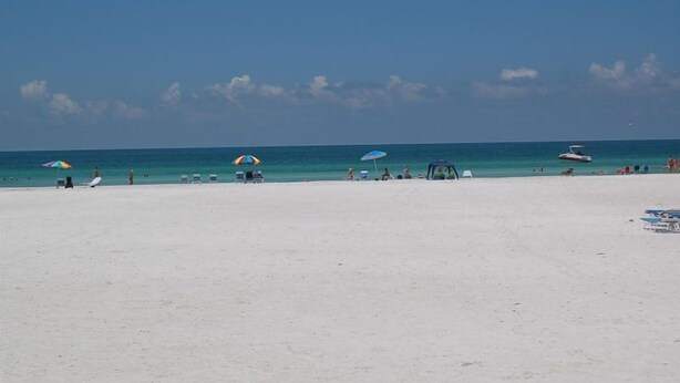 A beach with umbrellas, lounge chairs, and a clear blue sky. - Ground-level Condo near Beach and Shops - Casa Siesta 2 (Siesta Key)