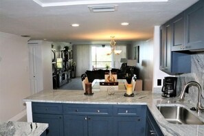 A modern kitchen with a central island, dark blue cabinets, and a stainless steel sink.