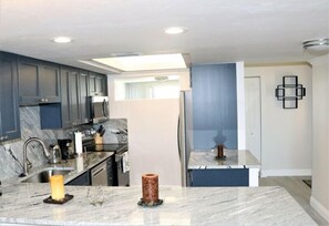 A modern kitchen with grey cabinets, a marble countertop, and a built-in oven.
