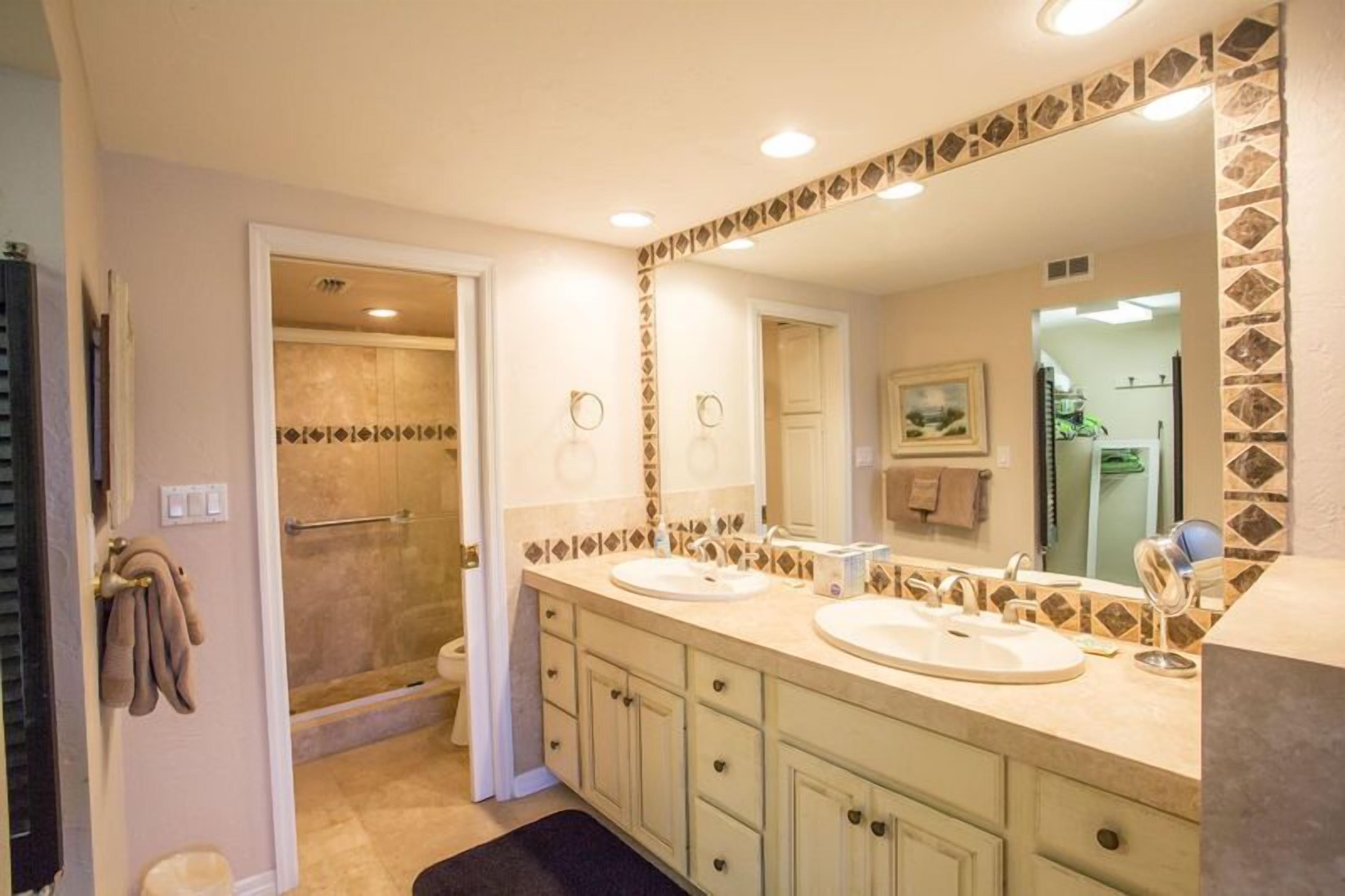 Une salle de bain avec deux lavabos, une douche et un grand miroir.