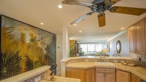 A kitchen with a large island, wooden cabinets, and a ceiling fan. - Gulf and Bay Club- A207 Updated! (Siesta Key)