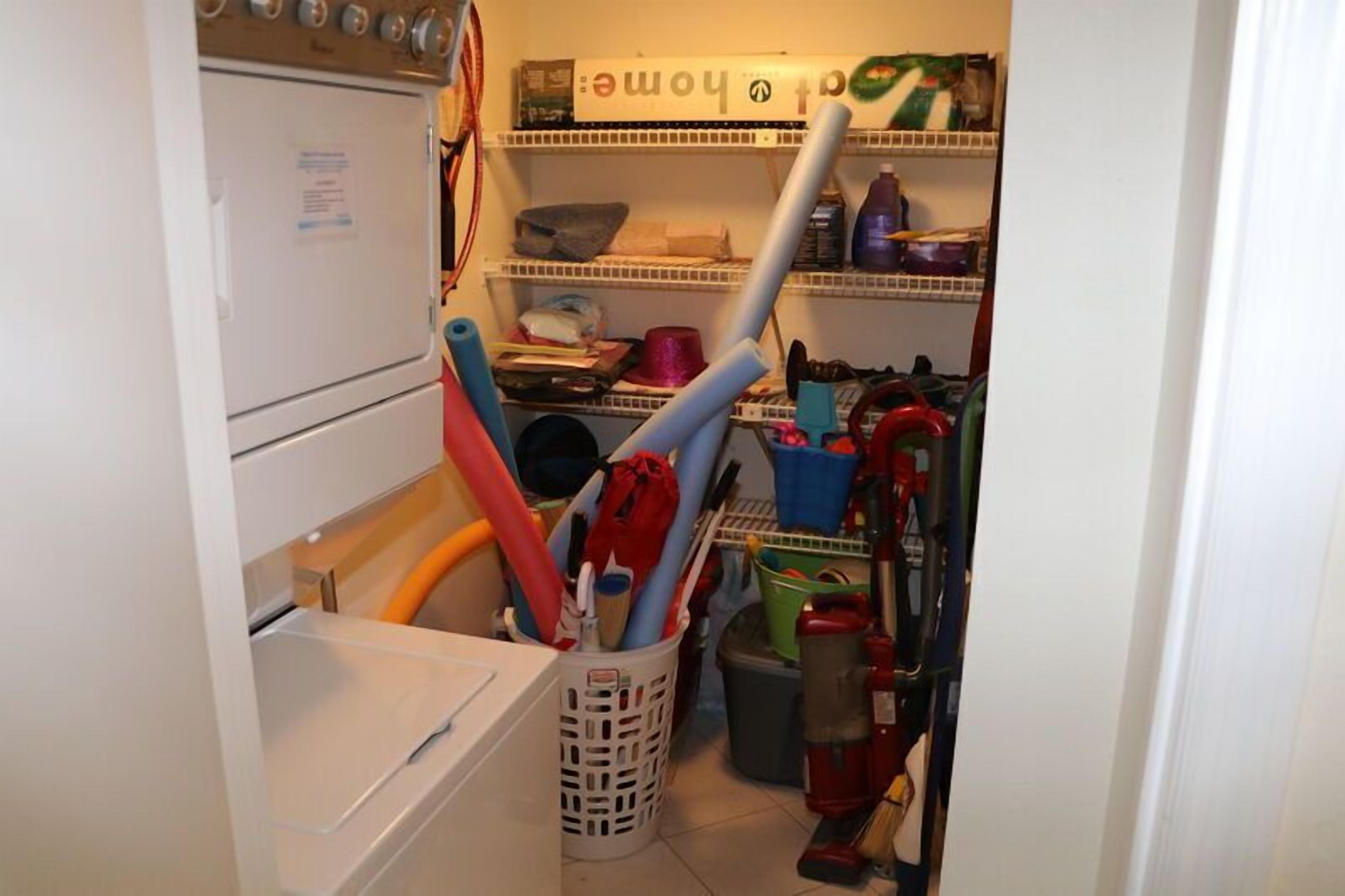 A laundry room with a washing machine, a dryer, and various cleaning tools and supplies.