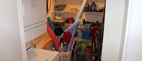 A laundry room with a washing machine, a dryer, and various cleaning tools and supplies.