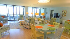 Un espace de vie lumineux et ouvert, avec une table à manger entourée de chaises, un canapé et un téléviseur.