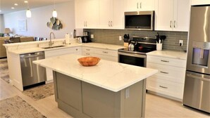 Een moderne keuken met witte kasten, roestvrijstalen apparatuur en een marmeren eiland.