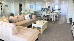 A spacious living area with a large sofa, a dining table with chairs, and a kitchen area in the background. - Gulf and Bay Club- A503 Updated with great view! (Siesta Key)