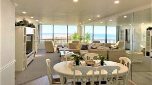 A spacious living room with a large dining table, comfortable seating, and a view of the ocean. - Gulf and Bay Club- A503 Updated with great view! (Siesta Key)