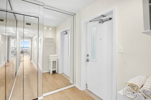 Une chambre d’hôtel avec une paroi en verre, une porte blanche et une vue sur la mer.