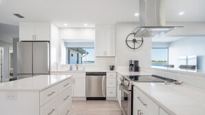 Una cocina moderna con armarios blancos, electrodomésticos de acero inoxidable y un amplio ventanal con vistas.