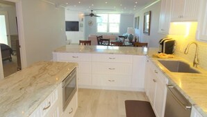 Una cucina moderna con mobili bianchi, un piano di lavoro in marmo e un forno integrato.
