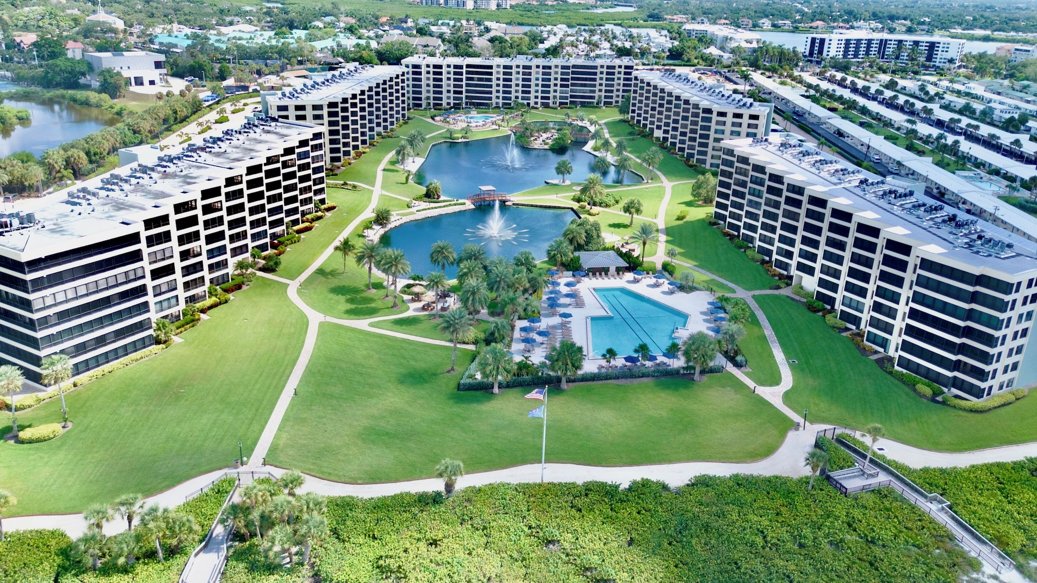 A large hotel complex with multiple high-rise buildings, a central courtyard with a swimming pool, and surrounding greenery.