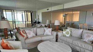 A modern living room with a beige sofa set, a round coffee table, and a glass partition.